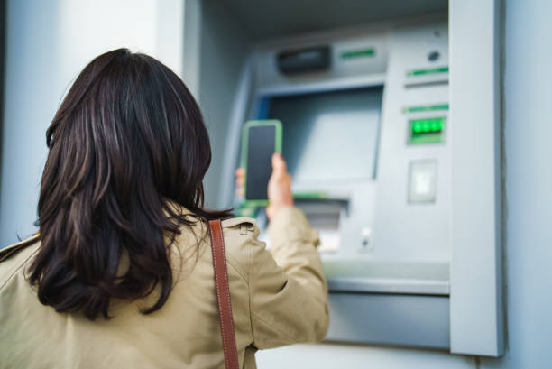 istock Part of a Series of an Asian Woman, using mobile phone on ATM 2024946406