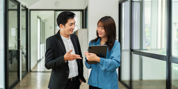istock Asian woman and business man working using digital tablet tech discussing financial market data standing at corporate office 2024958280