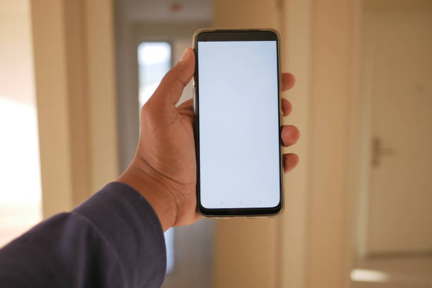 istock close-up hand using phone showing white screen in empty room 2025024579