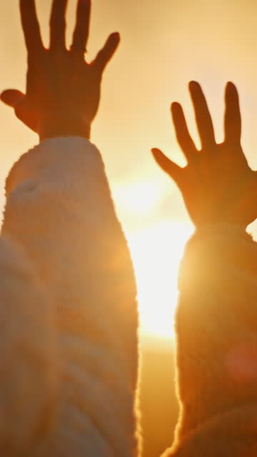 Young Women With Hands Raised Toward Golden Sunlight At Sunrise