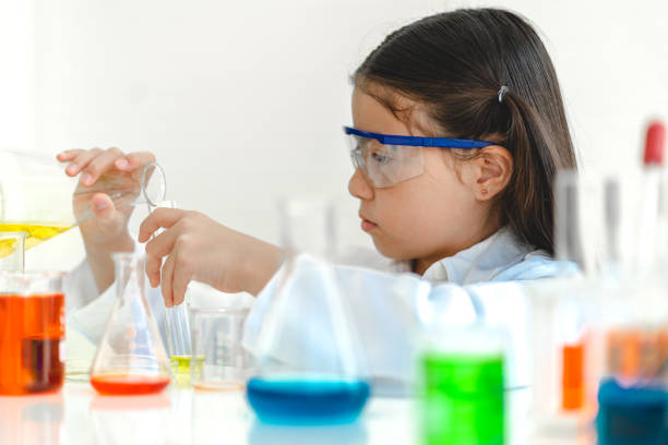 istock Cute little girl student child learning research and doing a chemical experiment while making analyzing and mixing liquid in glass at science class on the table.Education and science concept 2025054918