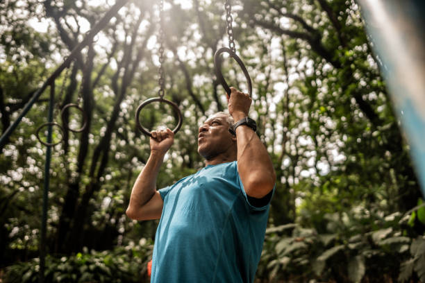 Senior man using gymnastic rings on the public park