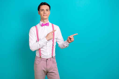Photo portrait of pretty young male point empty space banner shopping wear trendy pink outfit isolated on cyan color background.