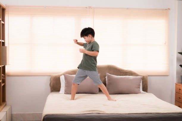 istock Happy asian elementary school boy jumping and dancing on bed, kid jumped and stomped around joyfully alone in bedroom without feeling tired. little boy have fun on the weekend. healthy child concept. 2025090488