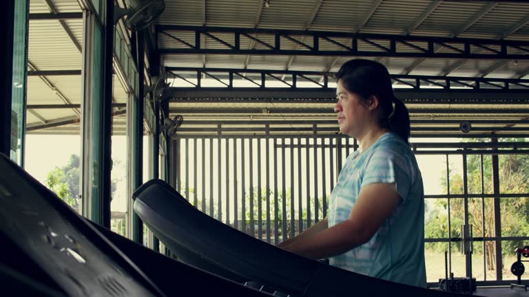 Asian plump woman walks and exercises on a treadmill inside the gym, Burn fat to lose weight