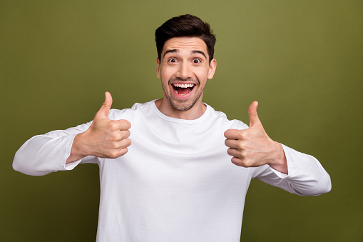 Portrait of astonished attractive guy open mouth demonstrate thumb up isolated on khaki color background.