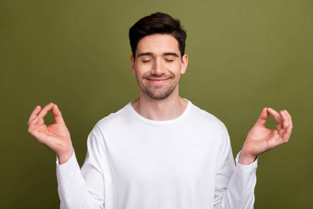 istock Portrait of young handsome brunet man wearing basic white long sleeve closed eyes and practice yoga pose isolated on khaki color background 2025110471