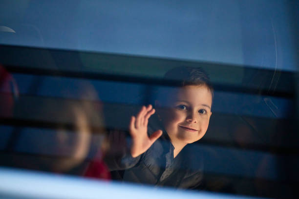 A young boy enjoys a car ride, captured through the window, as he observes the passing scenery