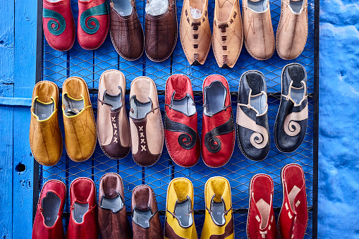 Blue wall with colored leather sandals in Chefchaouen, Morocco, North Africa.