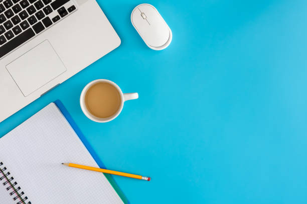 istock Laptop with notebook and cup of coffee on blue background. 2025152503
