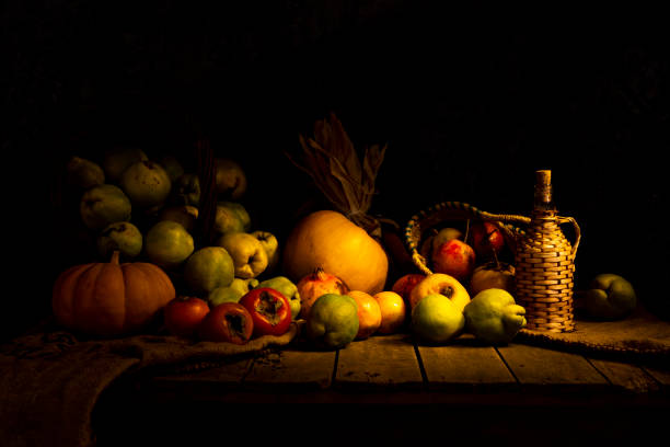 istock Autumn still life with different fruits such as pumpkin, grapefruit, pomegranate, corn and persimmons next to a traditional wooden covered bottle on wooden table and dark background. Horizontal. 2025165845