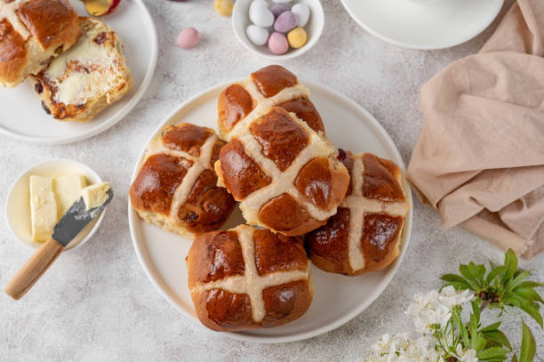 Traditional Easter hot cross buns on a white plate with butter, berry jam and cup of tea. Delicious Easter breakfast. ストックフォト