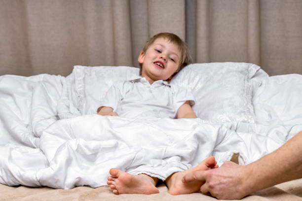 istock Children's feet under a blanket are tickled by dad's hand 2025219434