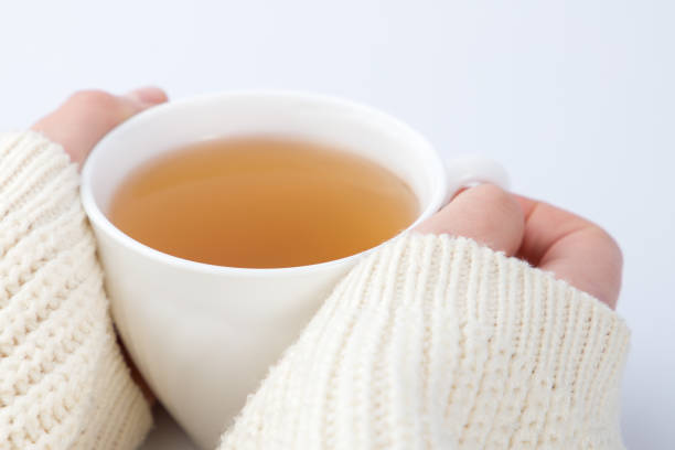 istock cup of tea with a knitted sweater on a female hand. 2025246741