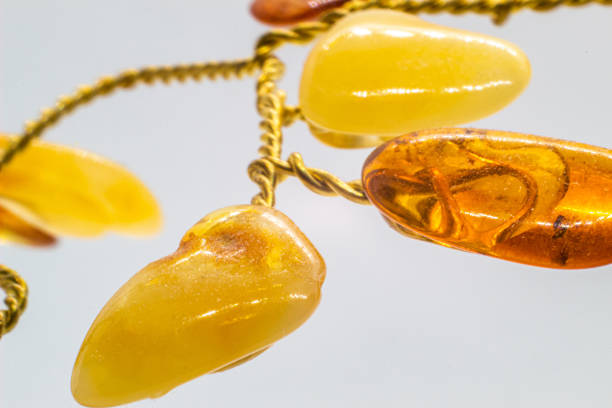 Vibrant yellow and orange polished amber crystal and copper wire tree on a blue chalcedony mineral base macro isolated on white surface