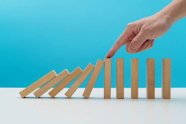 istock Man hand stopping the dominos falling 2025248932