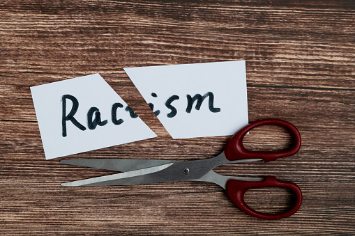 Scissor cutting paper with word racism
