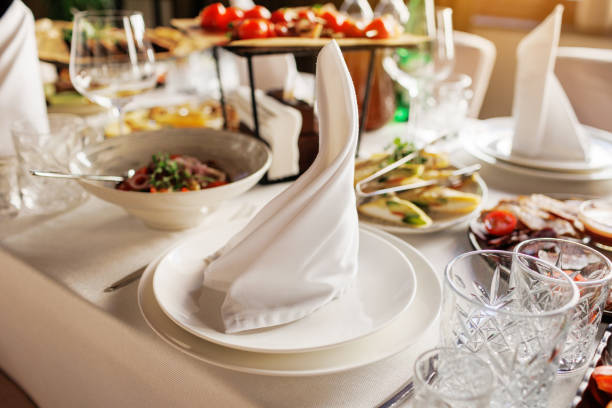 istock Festive serving, setting table. Plate decorated white napkin, cutlery, empty crystal wine glasses and different tasty meals. Wedding set up, dinner table reception. Birthday, baptism, event. Catering 2025269971