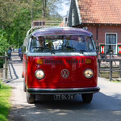 Netherlands, Overijssel, Twente, Denekamp, Singraven, May 27th 2023, a restored red Dutch 1979 Volkswagen Transporter 2nd generation Type 22 approaching at the Singraven watermill on a sunny day in springtime, the Transporter has been made by German manufacturer Volkswagen since 1950