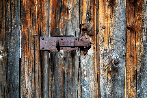 Weathered old wooden door locked with rusty metal iron latch.