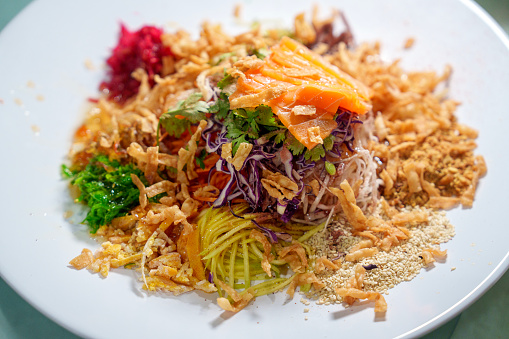 Chinese Yee Sang, also known as Yu Sheng, is a traditional dish served during Chinese New Year celebrations in some parts of Asia, particularly in Malaysia and Singapore. It is a colorful salad consisting of various ingredients such as shredded vegetables, pickled ginger, pomelo, raw fish slices (typically salmon or sometimes other types of fish), crackers, and various sauces and condiments.