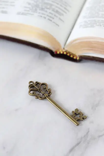 Ancient key with open holy bible book. Selective focus. Christian biblical concept of salvation, answered prayer, prophecy, revelation, and kingdom of God Jesus Christ.