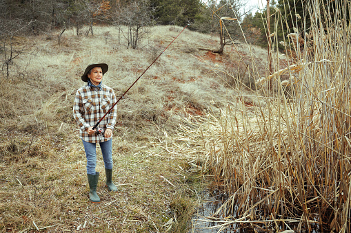 Senior woman fishing in nature alone