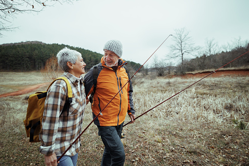 Senior couple walking while carrying fishing poles