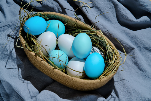 Easter composition in blue shades. Painted eggs in a basket. High quality photo.