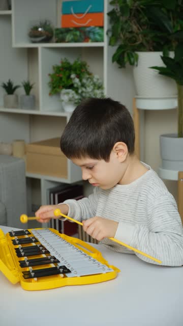 A six-year-old child plays a metallophone, a percussion musical instrument