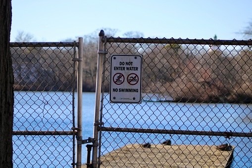 A sign posted on a metal gate that says no swimming.