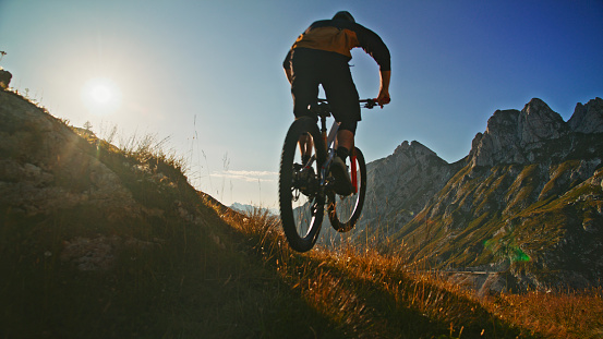 An Active Man Enjoys the Thrill of Riding his Bicycle Along the Rugged Paths of a Mountain,Feeling the Warmth of the Sun against his Skin and the Wind Rushing Past him Under the Expansive Blue Sky.