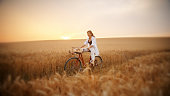 Happy Woman Enjoying A Bicycle Ride Amidst Wheat Field