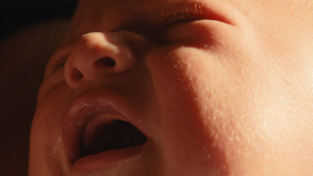 In a Close-Up Shot,Sunlight Bathes the Face of a Baby Boy as Tears Stream Down,Capturing a Moment of Innocence and Vulnerability Amidst the Gentle Glow of the Sun.