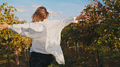 Rear View Carefree Woman with Arms Outstretched in Vineyard