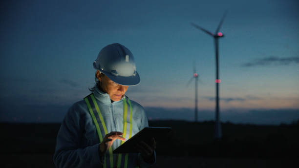 istock Female Engineer Analyzing Wind Turbines with Digital Tablet at Dusk 2025408761