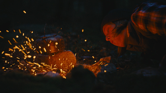 With Meticulous Care,a Woman Sets Up the Campfire and Prepares Food while Camping in the Forest at Night,the Crackling Flames Providing Both Warmth and Sustenance amidst the Darkness.