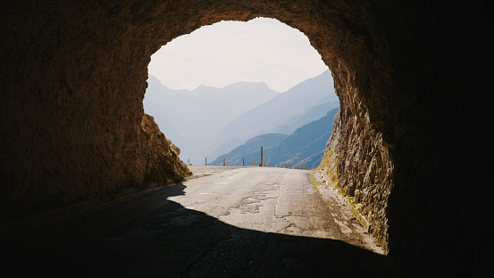 In the Tranquil Embrace of Mountains,Rocky Tunnel as a Portal for Sunlight,Illuminating the Rugged Path Within,Offering Serene Passage Amidst the Mountains and Lush Valleys.