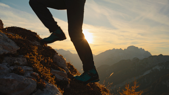 a Female Hiker Climbs the Towering Mountain against the Backdrop of the Setting Sun,her Determination Mirrored in Each Deliberate Step she Takes,the Vibrant Sky a Breathtaking Canvas to her Awe-Inspiring Journey during her Vacation.