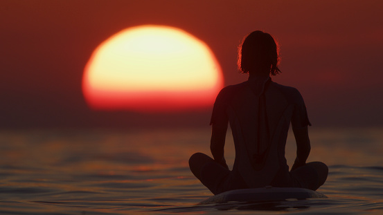 Active Woman Finds Solace,Meditating Peacefully on her Paddleboard. she Immerses Herself in the Serenity of the Moment,Harmonizing with the Gentle Rhythm of the Waves. It's a Serene Communion with Nature's Beauty.