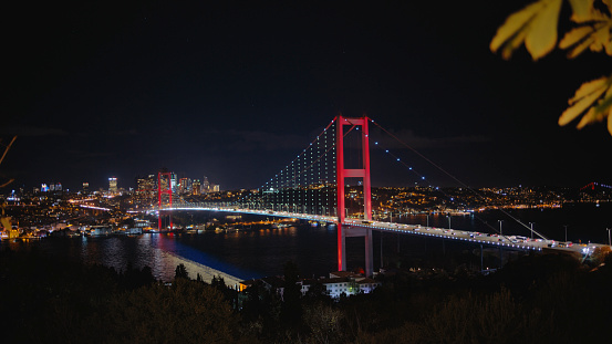 From a Commanding High Angle,the Illuminated Bosphorus Bridge Spans Gracefully over the Marmara Sea,by the Glittering Cityscape against the Backdrop of a Clear Night Sky. This Captivating Scene Encapsulates the Beauty and Modernity