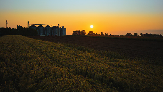 Lush Green Rural Field,Adorned With Silo Storage Tanks,Transforms Into A Captivating Scene As The Sun Sets,Casting A Warm Glow Over The Picturesque Landscape