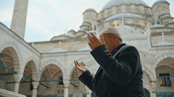 Captured From the Side,a Serene Moment Unfolds as a Mature Man Engages in Prayer Within the Tranquil Courtyard of the Blue Mosque,Set against the Backdrop of the Expansive Sky. His Reverent Posture and Focused Devotion Embody the Timeless Tradition of Spiritual Reflection at Istanbul,Turkey
