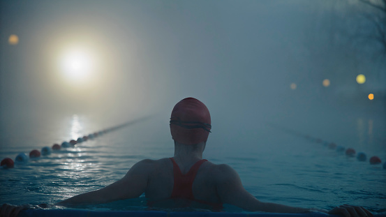 Amidst the Mist of a Tranquil Resort Morning,a Skilled Female Swimmer Enjoying the Calmness of the Resort Pool,Immersing Herself in the Soothing Embrace of Dawn.