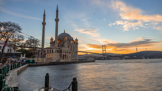 This Captivating Shot Captures the Breathtaking View of the Ortakoy Mosque and the Iconic Bosphorus Bridge against the Backdrop of a Stunning Sunset in Istanbul,Turkey. The Silhouetted Mosque,with its Intricate Architecture,Stands Elegantly by the Sea