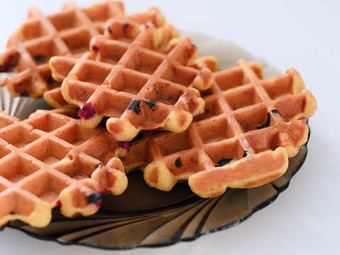 Homemade waffles on a plate on a white table.