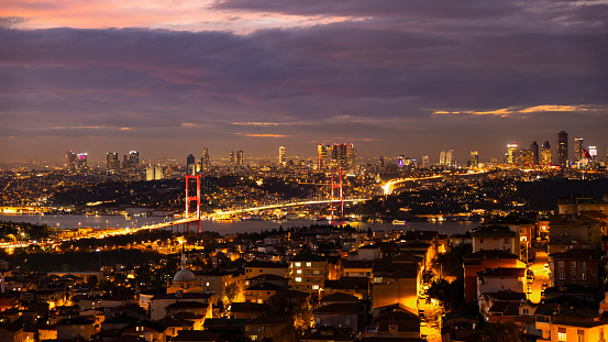 Gaze Upon the Enchanting Cityscape at Istanbul,Turkey and the Majestic Bosphorus Bridge Illuminated against the Backdrop of a Dramatic,Cloudy Night Sky,Offering a Captivating Aerial Perspective of Urban Charm and Architectural Grandeur