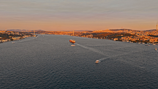 The Aerial View Captures the Serene Beauty of Istanbul,Turkey,as Boats Gracefully Move Across the Marmara Seascape. In the Background,the Iconic Bosphorus Bridge Stands Tall against the Cityscape,all Bathed in the Warm Glow of the Sunset. It's a Mesmerizing Scene of Urban Life