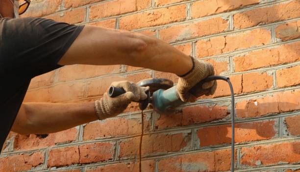 istock Construction worker with grinder cuts a line in a street brick wall 2025429258
