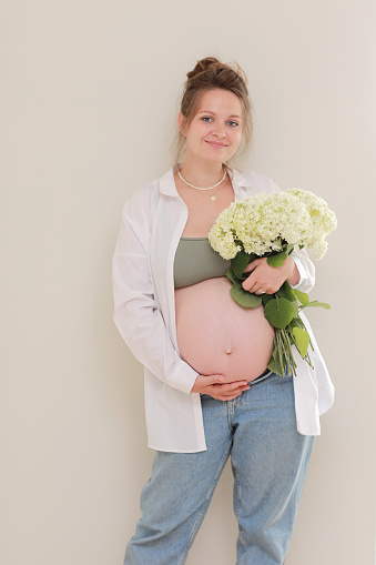 healthy pregnancy. Side view pregnant woman with big belly advanced pregnancy in hands. girl holding big bouquet of flower. copy space for text. Elegant mother waiting baby. selective focus